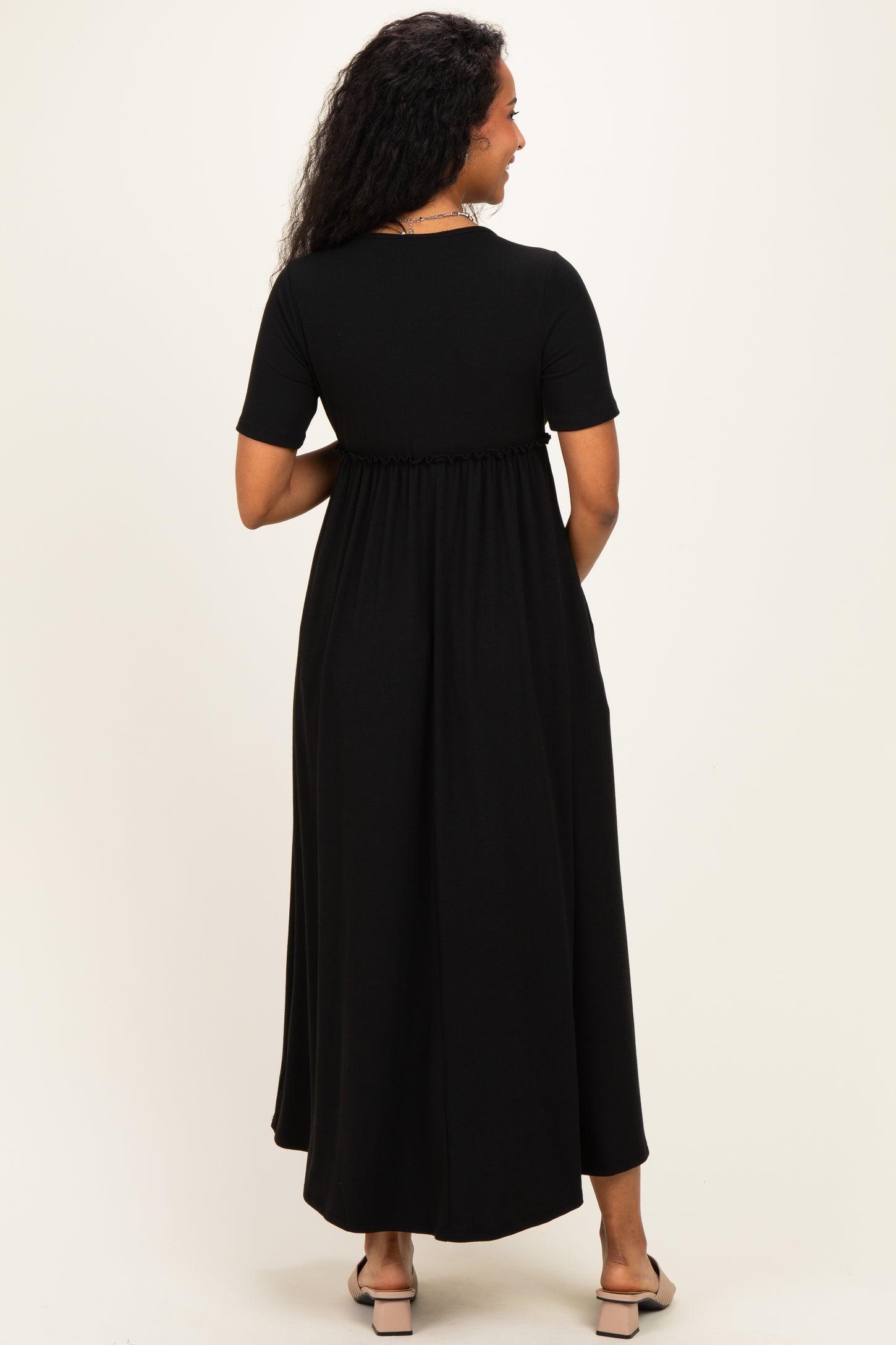 woman wearing a black short sleeve maternity maxi dress with a cinched waist and flowing skirt, showing her back