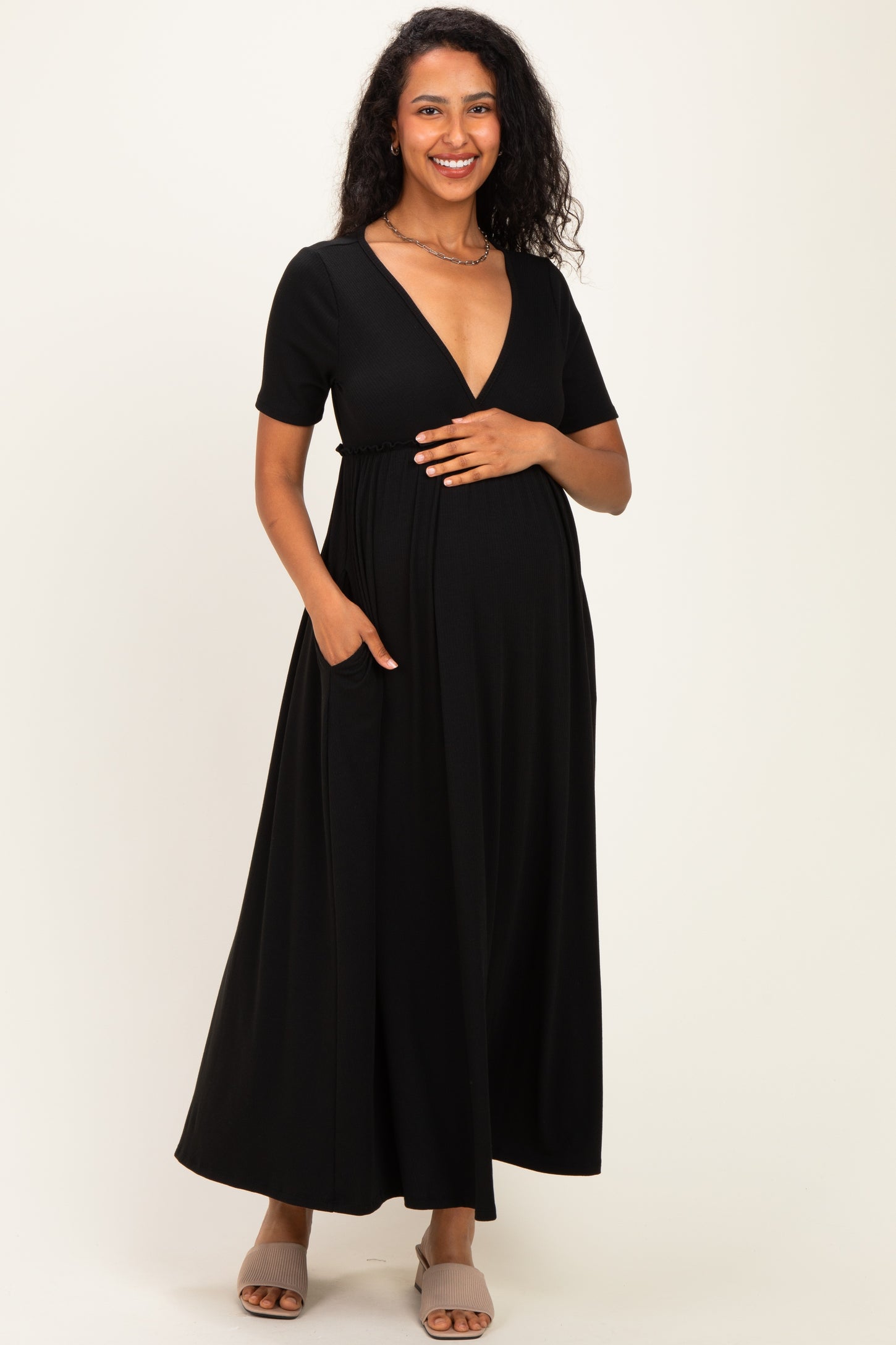 woman wearing a black short sleeve maternity maxi dress and holding her baby bump with a smile