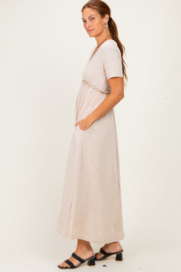 woman wearing a beige short sleeve maxi dress with side pockets and a cinched waist