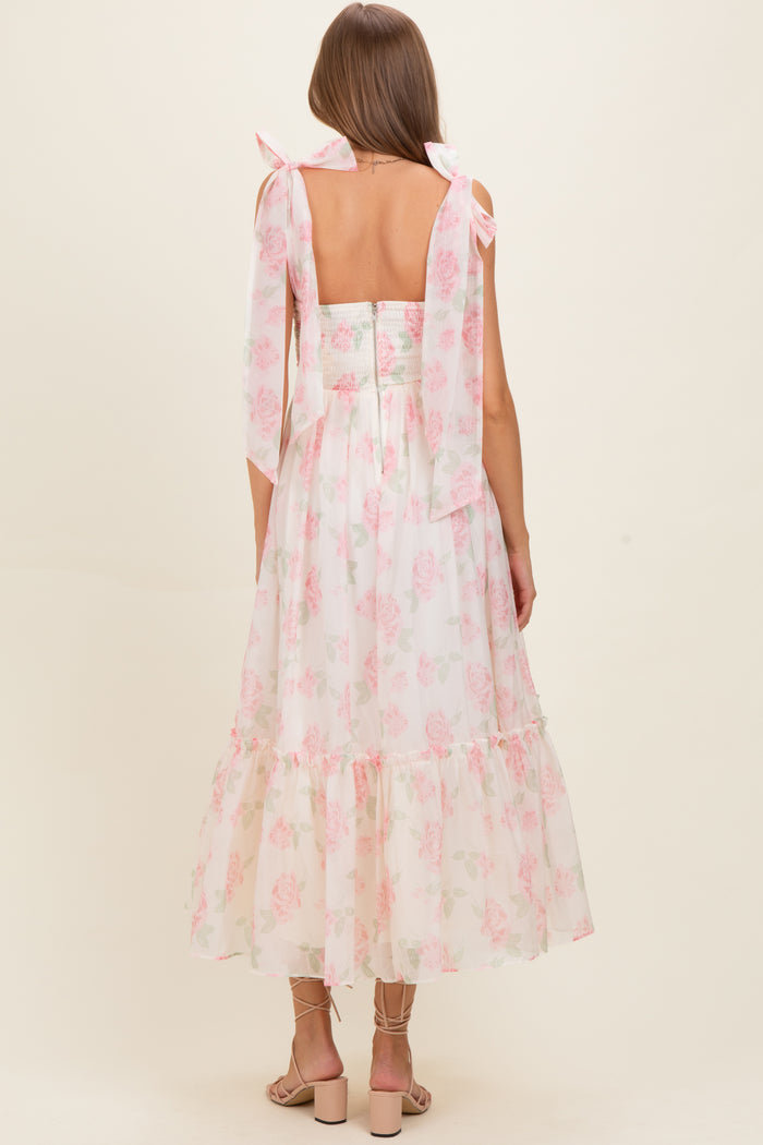 woman wearing a backless light pink floral maternity dress with flowy skirt and tied shoulder straps