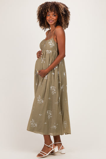 woman wearing an olive green floral print maternity maxi dress and holding her baby bump