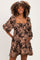 woman wearing a brown floral maternity dress with puff sleeves and a visible baby bump