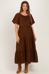 woman wearing a brown maternity maxi dress with short puff sleeves and tiered ruffle details