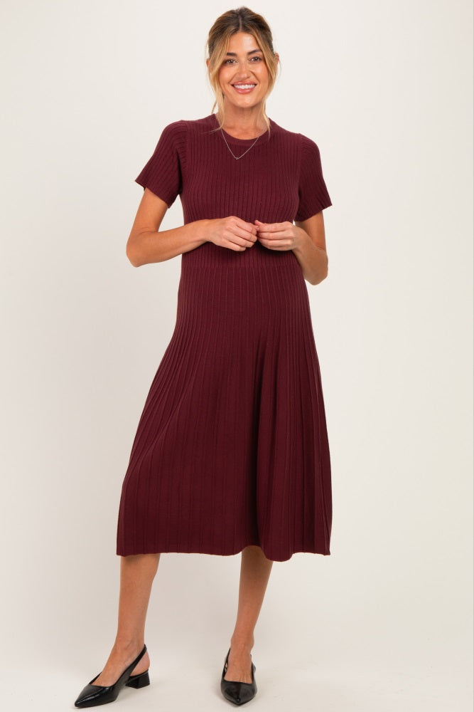 woman wearing a burgundy short sleeve ribbed maternity dress with a flared skirt and a baby bump visible