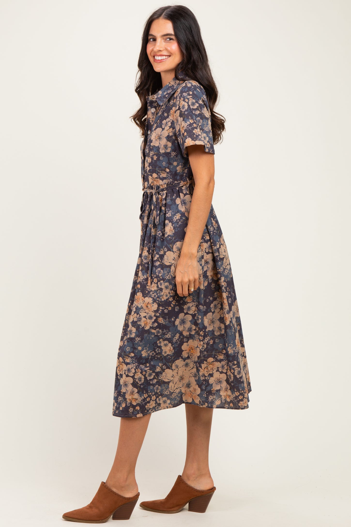 woman wearing a navy blue floral midi dress with short sleeves and a belted waist