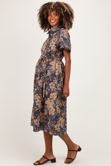 woman wearing a navy blue floral maternity dress with short sleeves and a tie waist, showing her baby bump