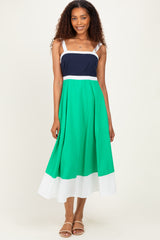 woman wearing a color-blocked midi dress with navy, green, and white sections and adjustable straps