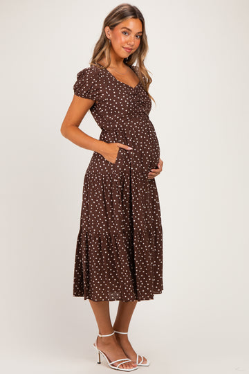 woman wearing a brown polka dot maternity dress with short sleeves and pockets, showing her baby bump