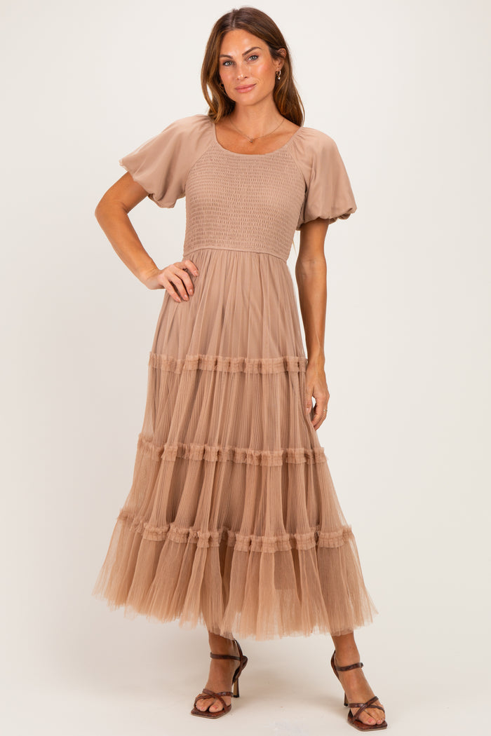 woman wearing a beige puff sleeve maxi dress with a smocked bodice and tiered tulle skirt