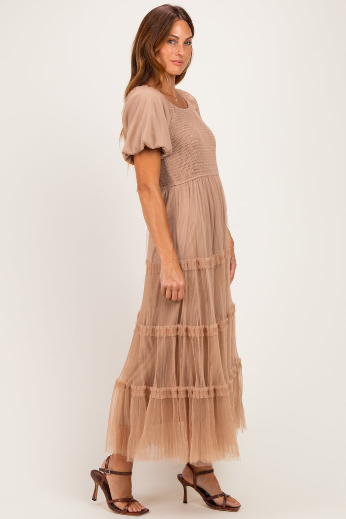 woman wearing a beige puff sleeve maxi dress with tiered tulle skirt and a smocked bodice, standing sideways