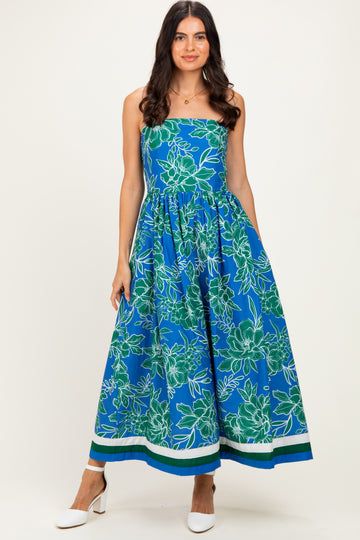 woman wearing a blue floral maxi dress with a fitted bodice and gathered skirt, styled with white heels