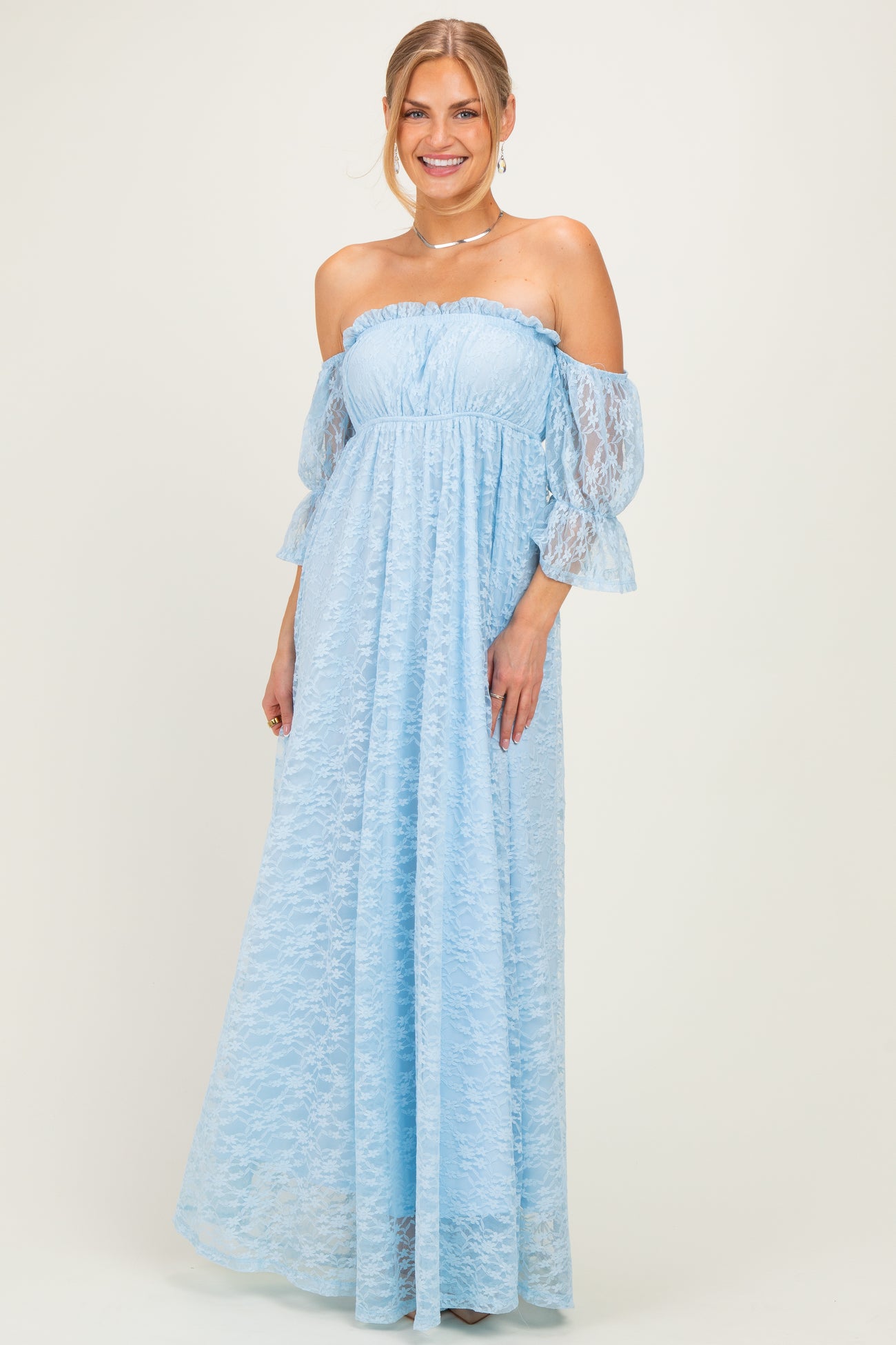 woman wearing a light blue off-the-shoulder lace maxi dress with bell sleeves and a fitted bodice