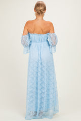 woman wearing a light blue off-the-shoulder maxi dress with lace details and long puff sleeves