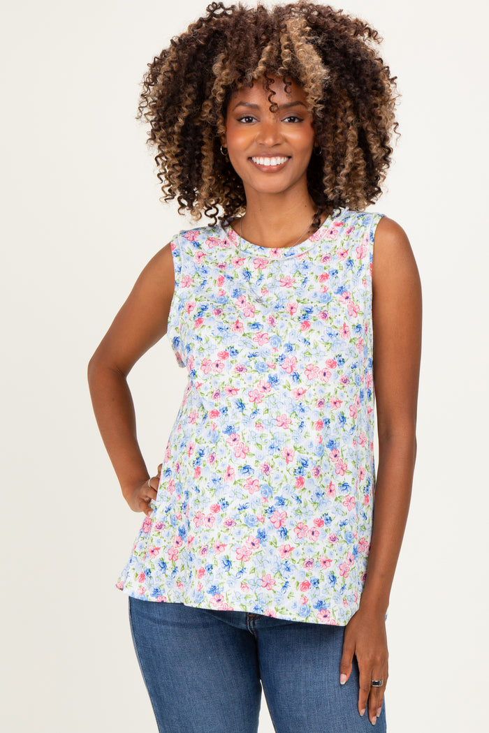 woman wearing a floral sleeveless maternity top with a relaxed fit and baby bump visible, paired with blue jeans