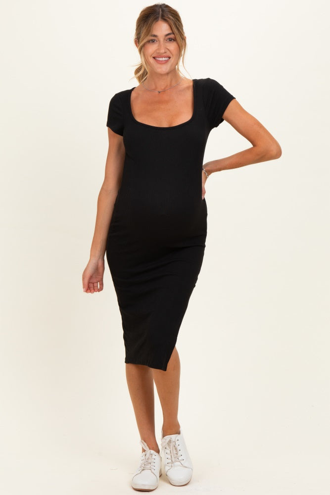woman wearing a black ribbed maternity dress with short sleeves and a scoop neckline, showcasing her baby bump