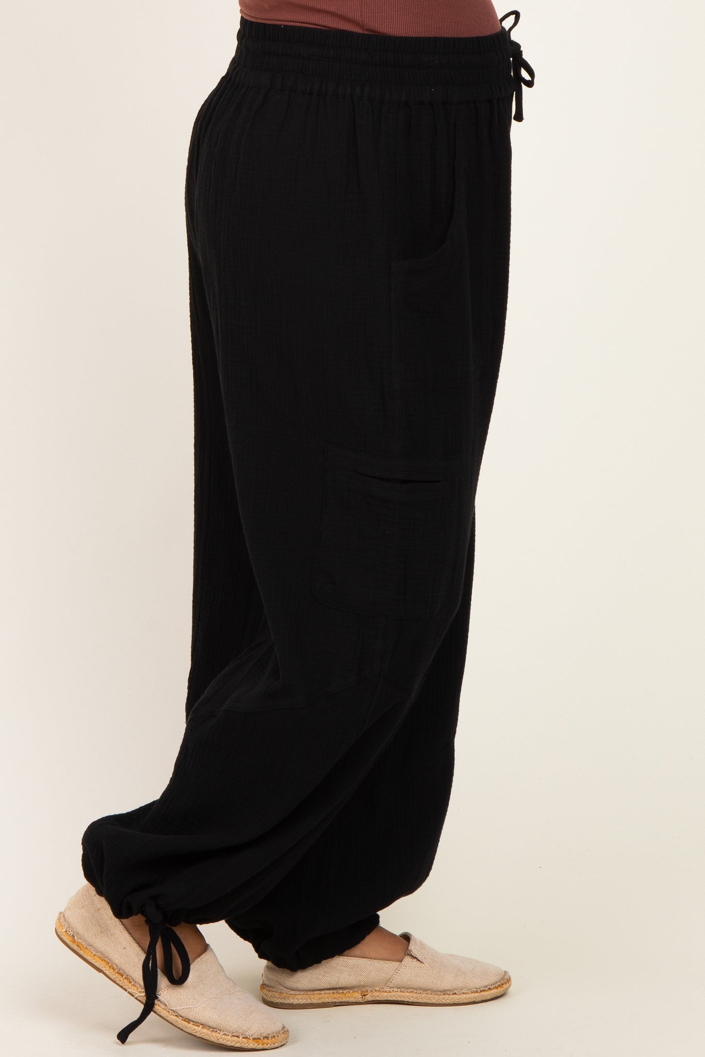 woman wearing black maternity wide-leg pants with pockets and a drawstring waist, side view