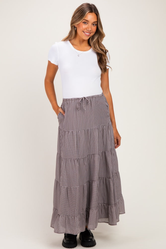 woman wearing a white short sleeve maternity top and a long black and white checked tiered skirt with pockets