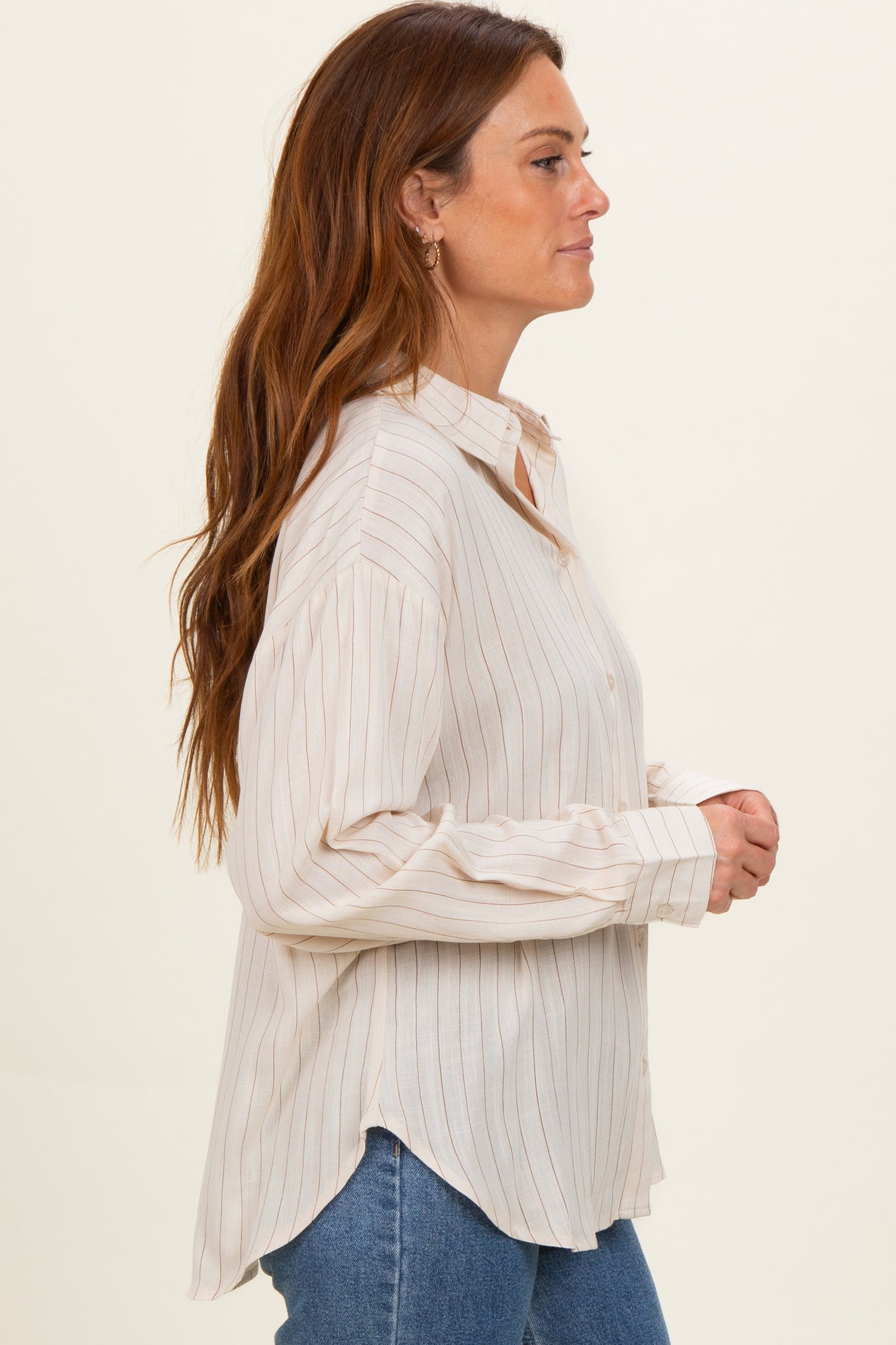 woman wearing a cream and rust striped button-up shirt with long sleeves and side slits