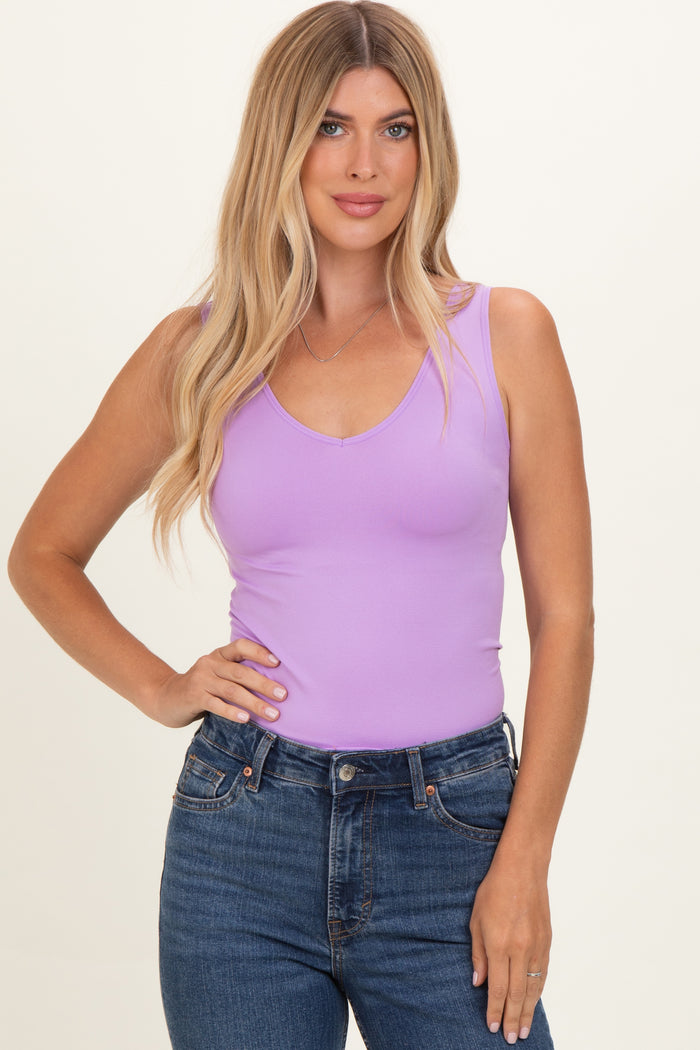 woman wearing a lavender v-neck tank top and high-waisted blue jeans