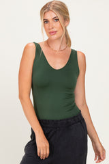 woman wearing a dark green sleeveless bodysuit with a v-neckline and black high-waisted pants