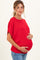 woman wearing a red oversized maternity top and holding her baby bump