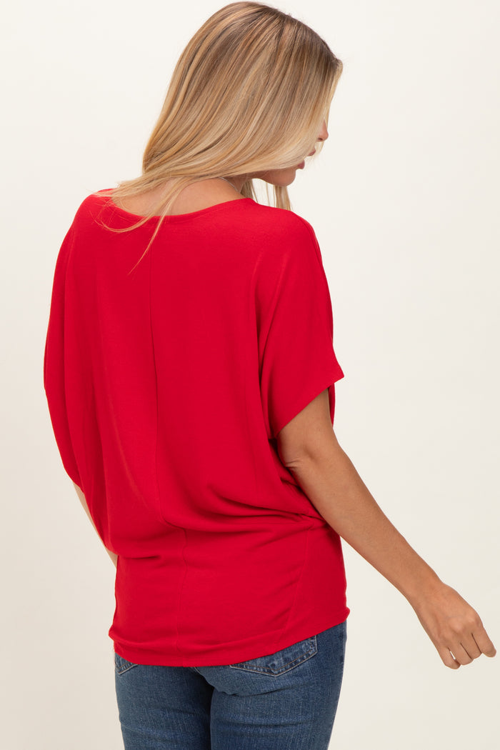 woman wearing a red short sleeve loose fit top with a relaxed back design and styled with blue jeans
