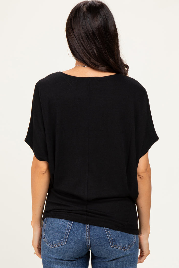 woman wearing a loose-fitting black top with short sleeves and back seam detail, paired with blue jeans