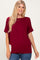 woman wearing a maroon oversized short sleeve top with a round neckline and relaxed fit paired with blue jeans
