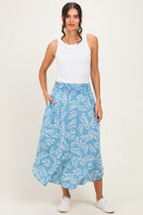 woman wearing a white tank top and a blue floral print maxi skirt with an elastic waistband and pockets