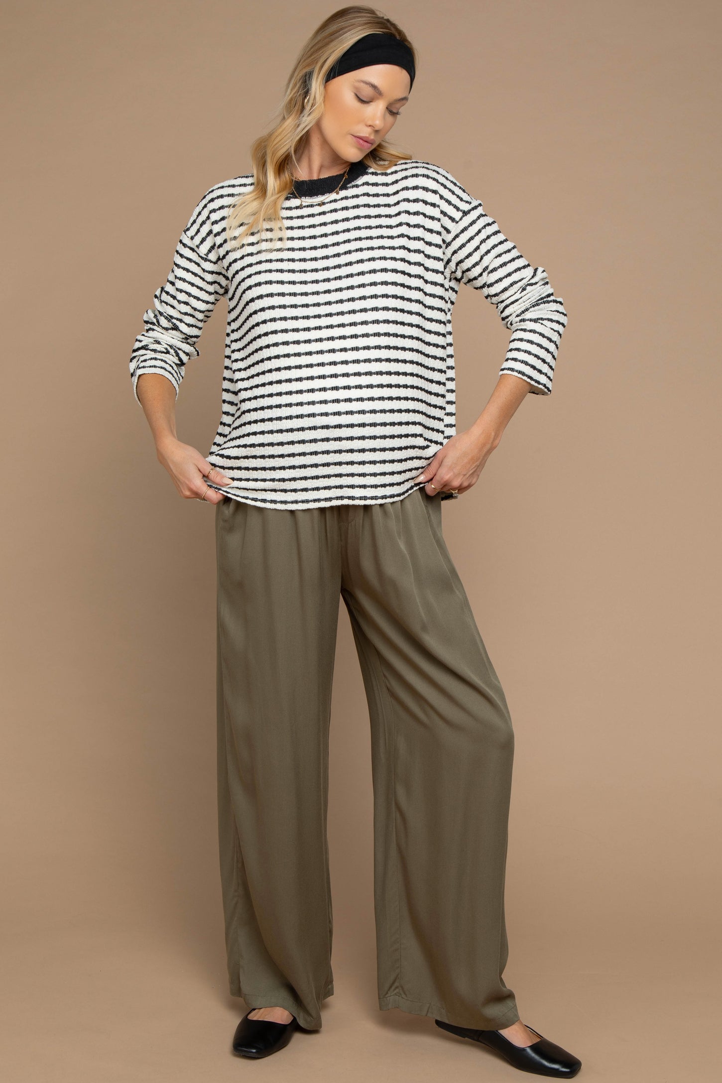 woman wearing a striped maternity top with long sleeves and loose olive green maternity pants
