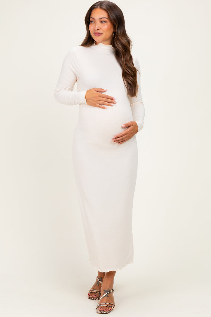 woman wearing a cream long sleeve maternity dress and holding her baby bump