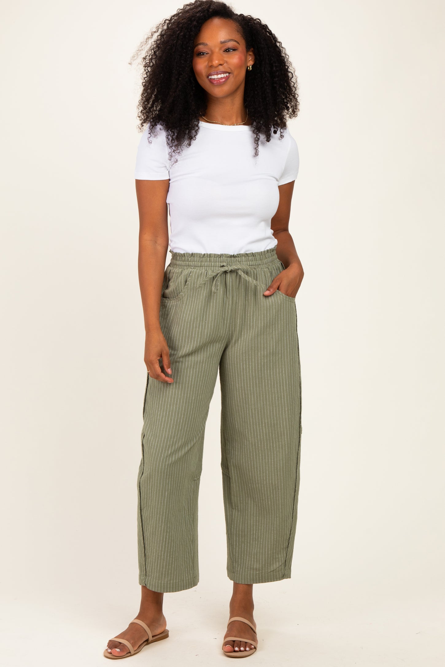 woman wearing a white short sleeve top and olive green striped wide-leg pants with side pockets