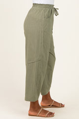 woman wearing olive green striped wide-leg pants with an elastic waistband and side pockets, paired with sandals