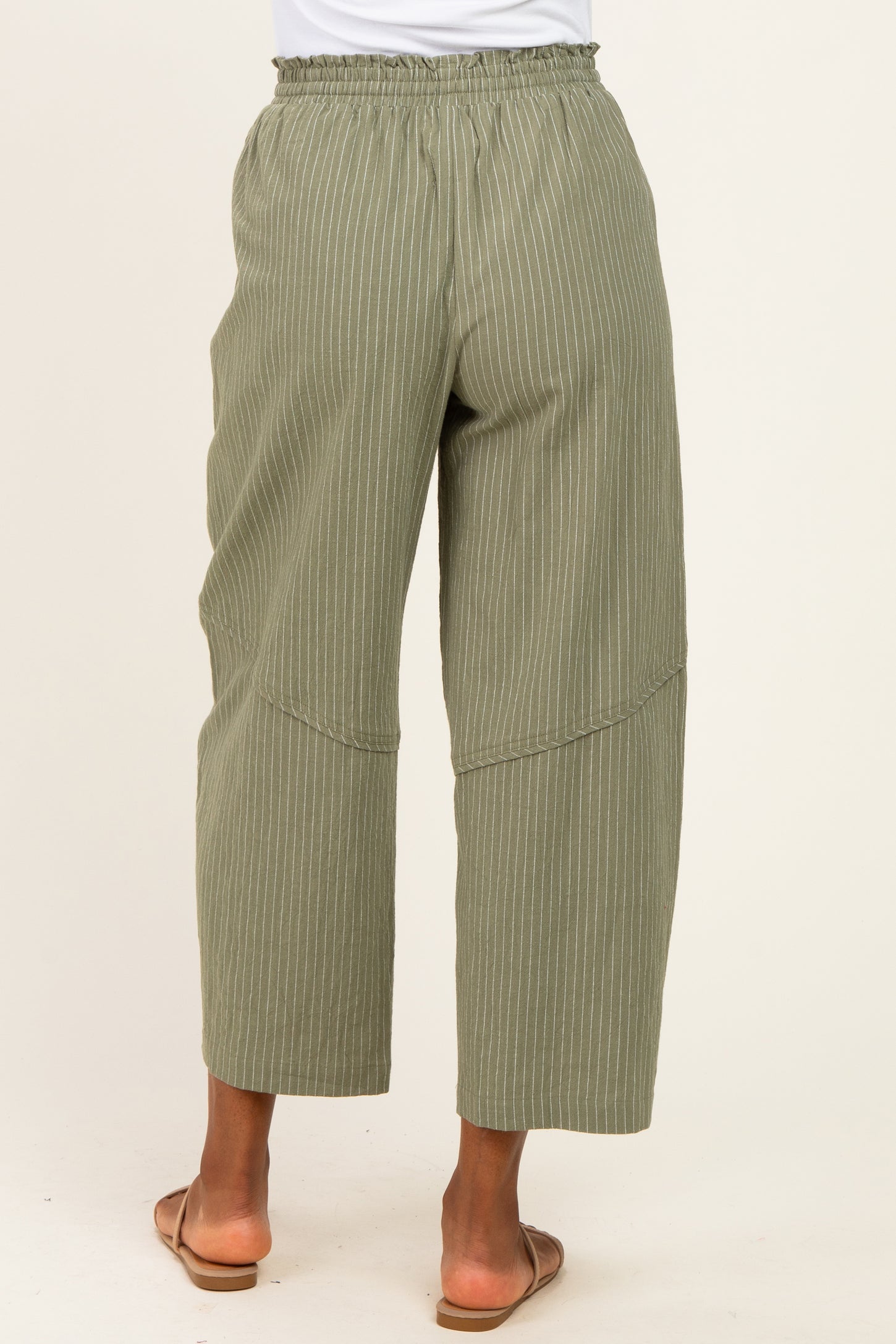 back view of woman wearing olive green striped wide-leg pants with an elastic waistband and side seams