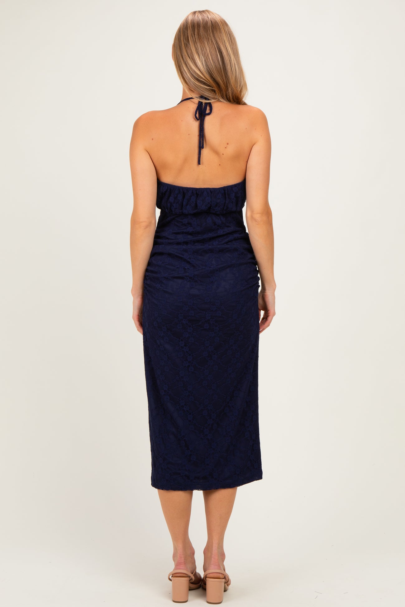 woman wearing a navy blue halter neck dress with a fitted bodice and a midi length, viewed from the back