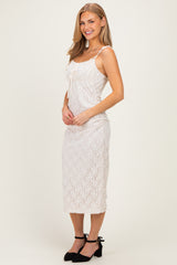 woman wearing a white lace midi dress with spaghetti straps and a fitted silhouette, smiling and standing sideways