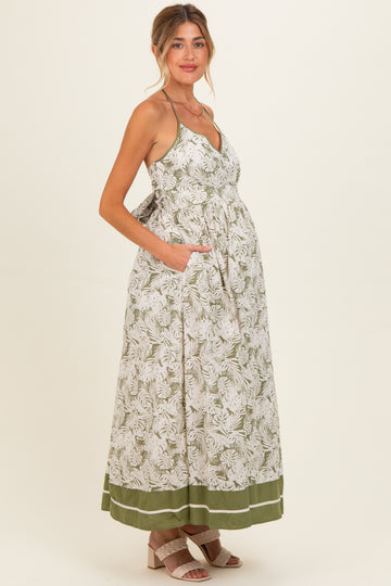 woman wearing a floral print maternity maxi dress with a tie waist and pockets, showcasing her baby bump