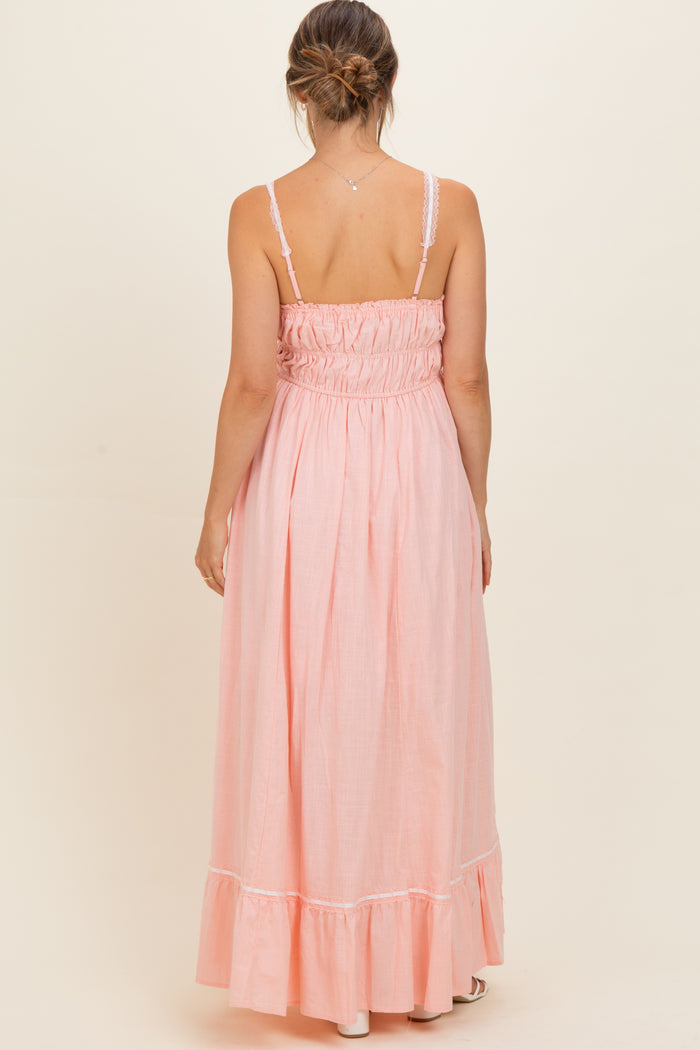woman wearing a pink maternity maxi dress with a smocked back and ruffled hemline