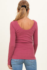 woman wearing a fitted ribbed maternity top in dark pink with a scoop back and long sleeves, styled with jeans