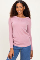 woman wearing a light pink ribbed long sleeve top and blue jeans with a relaxed fit