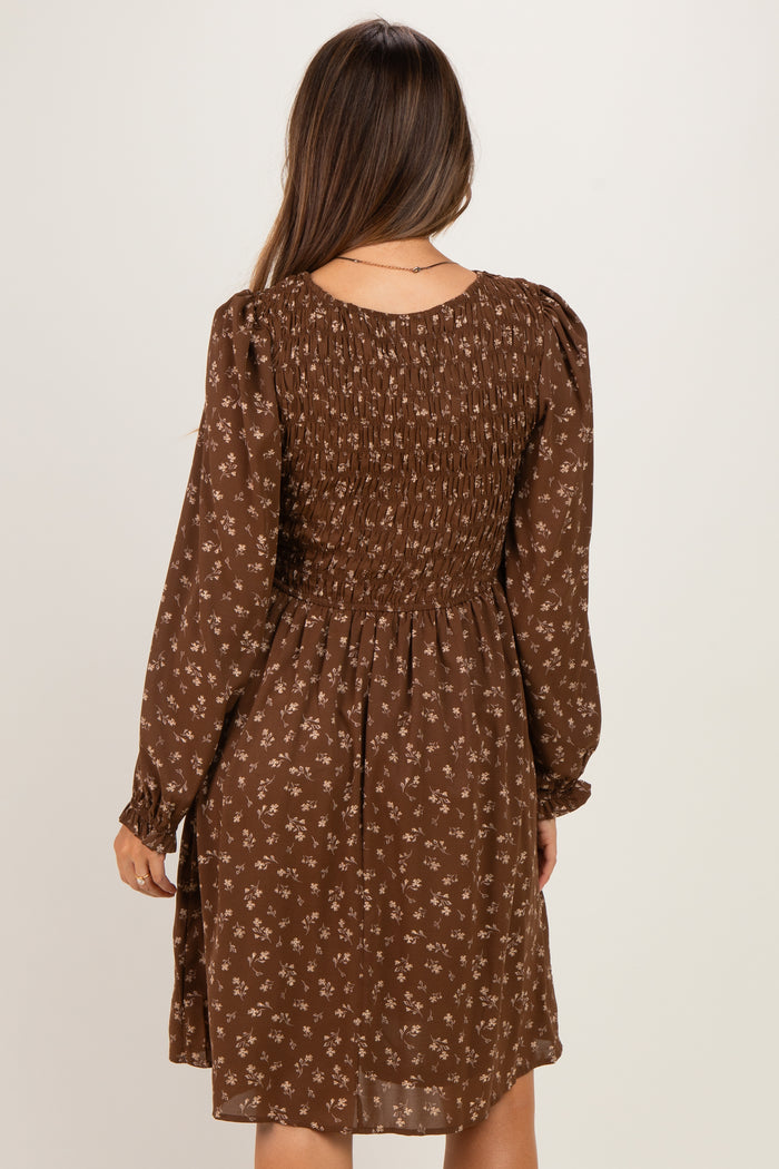 woman wearing a brown floral smocked maternity dress with long sleeves and a relaxed fit from the back
