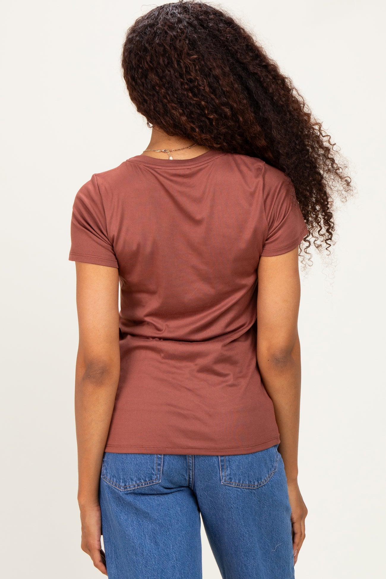 woman wearing a brown short sleeve top and blue jeans, viewed from the back