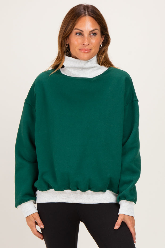 woman wearing a green oversized sweatshirt with a gray mock neck and cuffed sleeves