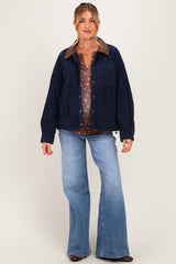 woman wearing a navy corduroy jacket over a brown floral maternity top and flared jeans, with a relaxed fit