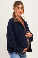 woman wearing a navy blue corduroy maternity jacket over a brown floral top and holding her baby bump