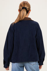 woman wearing a navy blue corduroy maternity jacket with a brown collar, viewed from the back