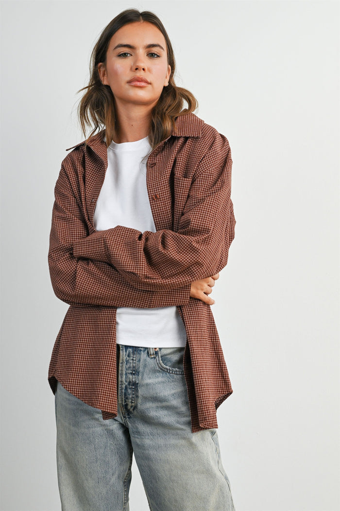 woman wearing a brown checkered oversized button-up shirt with a white t-shirt and light blue jeans