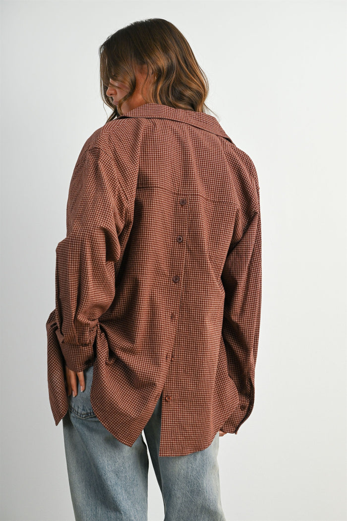 woman wearing a brown checkered oversized button-up shirt with a back button detail and relaxed fit jeans