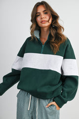 woman wearing a green and grey color block quarter zip sweatshirt with checkered pants