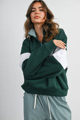 woman wearing a green and gray color block pullover sweatshirt with a half zip and matching checkered pants